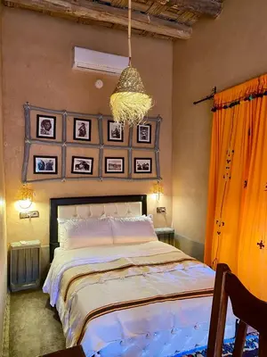 a bedroom with a large bed and a chandelier at Nomadic Birdway in Imiter