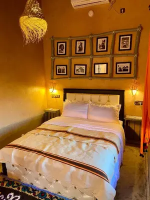 a bedroom with a large bed with pictures on the wall at Nomadic Birdway in Imiter