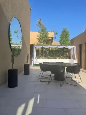 a patio with a table and chairs and a mirror at Villa M avec Piscine Chauffée in Marrakech