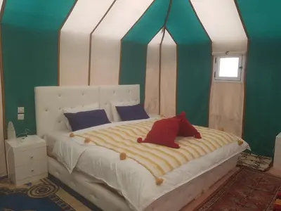 a bedroom with a large bed with a canopy at Merzouga Activities Camp in Merzouga