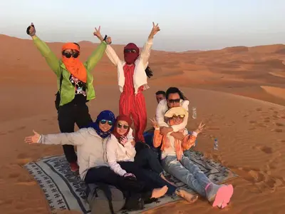 a group of people sitting in the desert at Merzouga Activities Camp in Merzouga