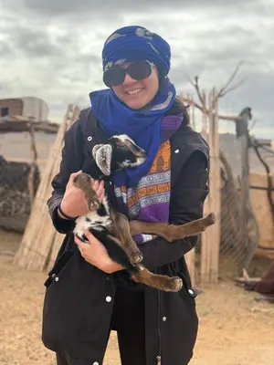 a woman is holding a baby goat at Merzouga Luxury Camp & Activities in Merzouga