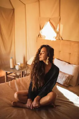 a woman sitting on top of a bed at Merzouga Luxury Camp & Activities in Merzouga