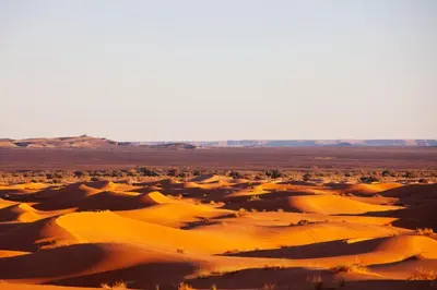 a desert with sand dunes and mountains in the background at Merzouga Luxury Camp & Activities in Merzouga