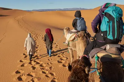 a group of people riding camels in the desert at Merzouga Luxury Camp & Activities in Merzouga