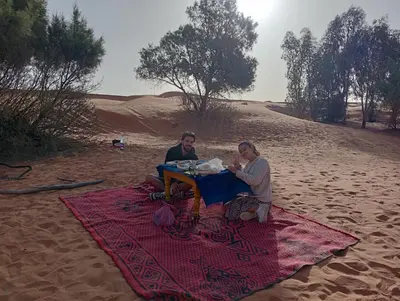 two people sitting at a table in the desert at Canadien camp merzouga in Merzouga