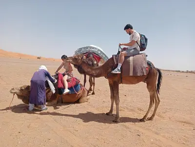 a group of people riding on a camel in the desert at Canadien camp merzouga in Merzouga