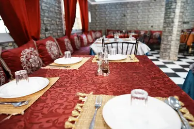 a dining room with a red table with plates and glasses at Hotel De La Vallée in Aït Baha