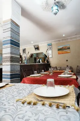 a dining room with two tables with red table cloth at Hotel De La Vallée in Aït Baha