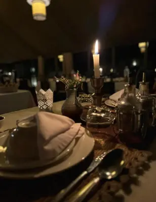 a table with a candle and plates and utensils at Merzouga Hamza Luxury Camp in Merzouga