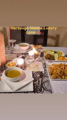 a table topped with plates and bowls of food at Merzouga Hamza Luxury Camp in Merzouga
