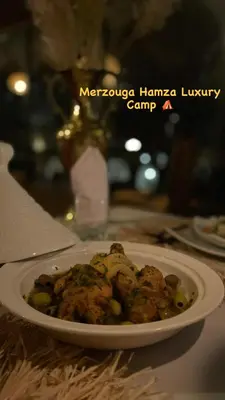 a plate of food with meat and vegetables on a table at Merzouga Hamza Luxury Camp in Merzouga