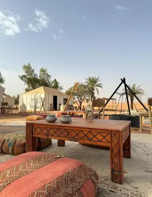 a wooden table with bowls on top of it at Merzouga Hamza Luxury Camp in Merzouga