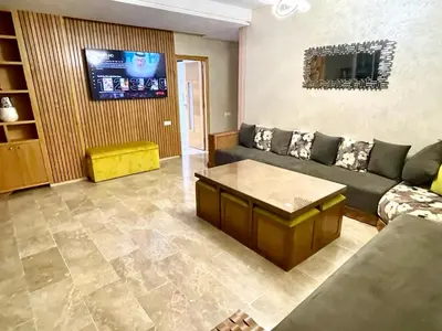 a living room with a couch and a tv at Bel appartement meublé avec Wifi fibre optique in Fès
