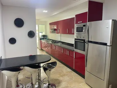 a kitchen with red cabinets and a table and a refrigerator at Bel appartement meublé avec Wifi fibre optique in Fès