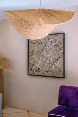 a painting hanging on a wall with a purple chair at Villa Naël Marrakech in Marrakech
