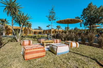 a group of ottoman chairs and a table and an umbrella at Villa Naël Marrakech in Marrakech