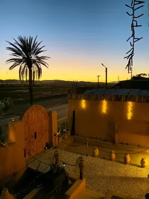 a palm tree and a building with the sunset in the background at CHÂTELET Ouarzazate in Tabount