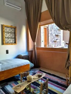 a bedroom with a bed and a window and a table at CHÂTELET Ouarzazate in Tabount