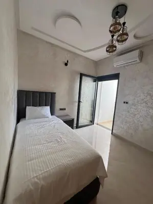 a bedroom with a white bed and a large window at Appartement luxueux à Fès in Douar Oulad Mhammed
