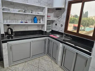 a kitchen with white cabinets and a window at Apparemment familiale 110 m2 in MeknèsKatine