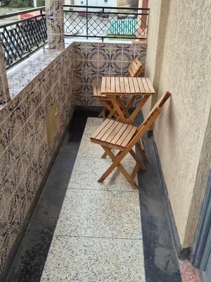 two wooden chairs and a table on a balcony at Apparemment familiale 110 m2 in MeknèsKatine