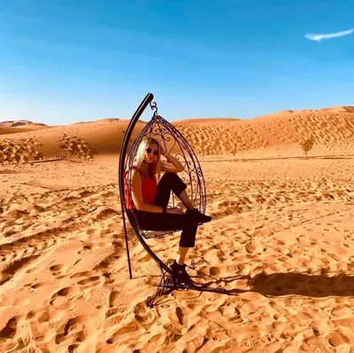 a woman sitting in a chair in the desert at Anir Luxury Camp - Gites et Tentes de Luxe in Merzouga