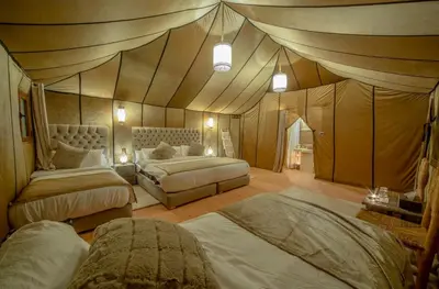 a bedroom with two beds in a tent style room at Anir Luxury Camp - Gites et Tentes de Luxe in Merzouga