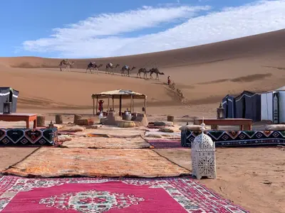 a desert with people and camels walking in the sand at Ali Baba Desert Camp in El Gouera