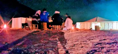 a group of people standing in front of tents at night at Ali Baba Desert Camp in El Gouera