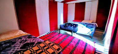 two beds in a room with red and white stripes at Ali Baba Desert Camp in El Gouera