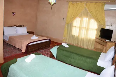 a hotel room with two beds and a television at Kasbat Dar diafa Tourbist in Kalaat MGouna
