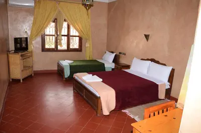 a bedroom with two beds and a television in it at Kasbat Dar diafa Tourbist in Kalaat MGouna