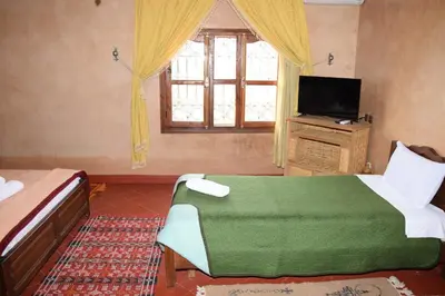 a bedroom with a bed and a television and a window at Kasbat Dar diafa Tourbist in Kalaat MGouna