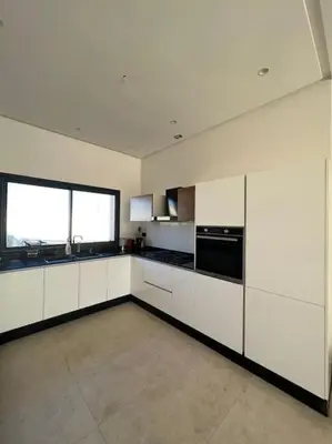 a large kitchen with white cabinets and a large window at Villa Mia, Piscine chauffée, parking,Iptv in Najem