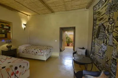 a bedroom with two beds and a table and a chair at Guest farm Oulad Chmicha in Bir el Kelb