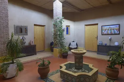 a room with potted plants and a fountain in the middle at Guest farm Oulad Chmicha in Bir el Kelb