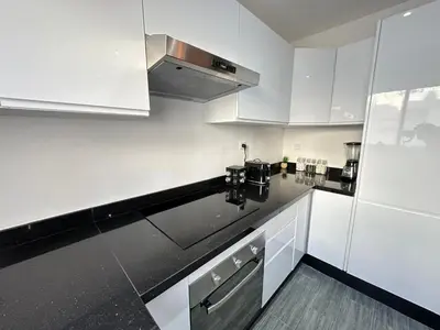 a kitchen with white cabinets and a black counter top at Appartement Moderne & Cosy in Fès