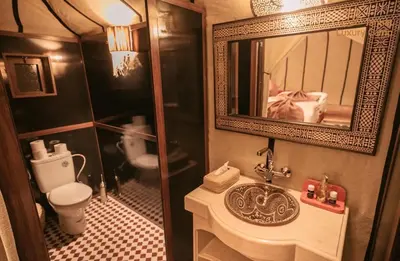 a bathroom with a sink and a toilet and a mirror at Merzouga Sardegna Luxury Camp in Merzouga