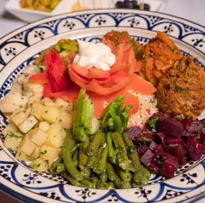 a plate of food with vegetables on a table at Merzouga Sardegna Luxury Camp in Merzouga