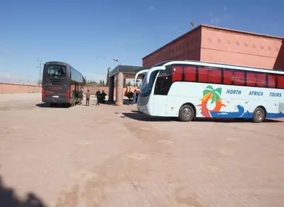 two buses parked in a parking lot next to a building at Hôtel Jnane Ain Asserdoune in Oulad Yaïch