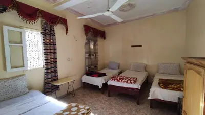 a room with three beds and a window at Hotel Oasis Tinghir in Tinerhir