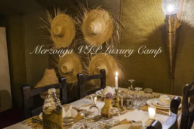 a table with a candle and some plates and glasses at Merzouga VIP Luxury Camp in Merzouga