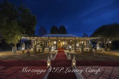 a building with lights in front of it at night at Merzouga VIP Luxury Camp in Merzouga