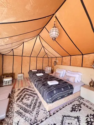 a bedroom with a bed in a tent at Merzouga VIP Luxury Camp in Merzouga