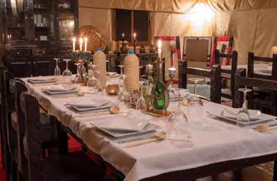 a long table with a white table cloth on it at Merzouga VIP Luxury Camp in Merzouga