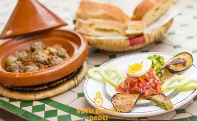 a plate of food with eggs and bread on a table at Hotel Babylon Dades in Imdiazene