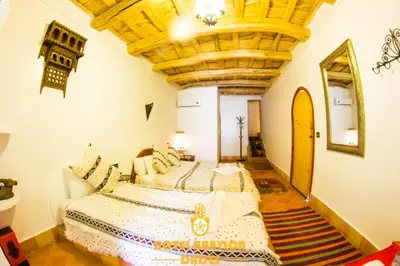 a bedroom with a large bed and a wooden ceiling at Hotel Babylon Dades in Imdiazene