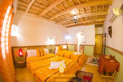 a bedroom with two beds and a table in it at Hotel Babylon Dades in Imdiazene