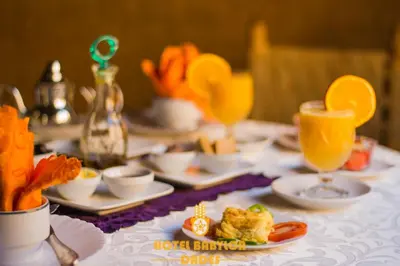 a table with plates of food and glasses of orange juice at Hotel Babylon Dades in Imdiazene